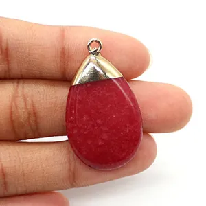 Detail of red teardrop natural stone pendant with gold clasp held by fingers for size