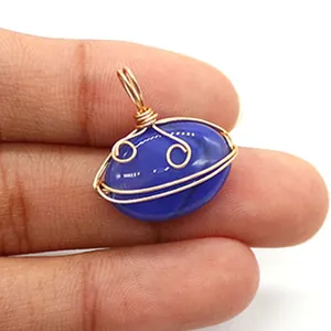 Macro detail of handmade gold wire-wrapped oval blue agate pendant with a smile design