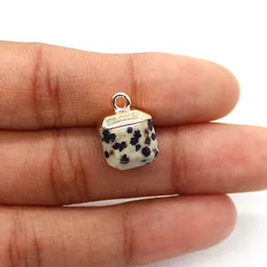 Detailopname van een gefacetteerde dalmatiër jaspis hanger met goudkleurige oog in de hand