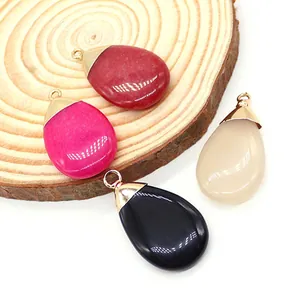 Set of four colorful teardrop stone pendants with gold bails on a wooden display