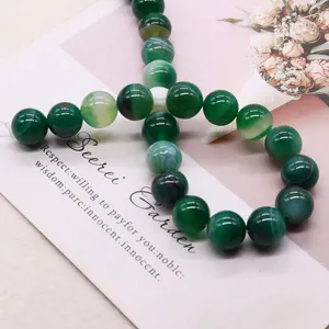 Natural green striped agate beads for DIY jewelry making on a floral background card