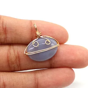 Macro detail of hand-wrapped gold wire on oval purple agate stone pendant held in hand