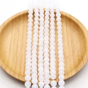 Polished natural white jade round beads for jewelry making displayed on a bamboo tray