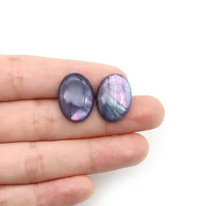 Nahaufnahme von ovalem Abalone-Muschel-Cabochon mit schillerndem lila Glanz auf der Hand