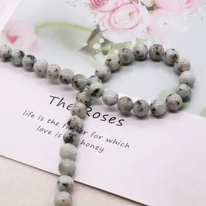 Polished natural stone beads with black spots arranged on vintage decorative card