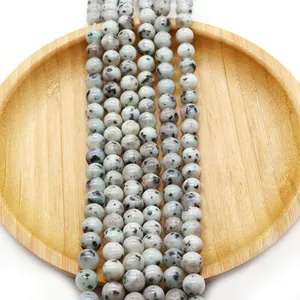Polished Dalmatian Jasper natural stone round beads on a wooden tray for jewelry DIY