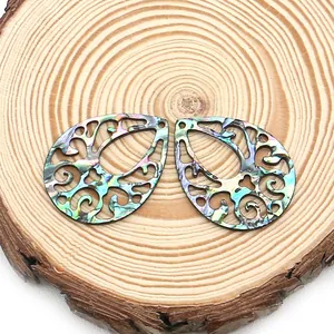 Hollow teardrop abalone shell pendants with pearlescent finish on a wooden base