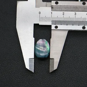 Makroansicht von ovalem irisierendem Muschel-Cabochon mit Messschieber gemessen