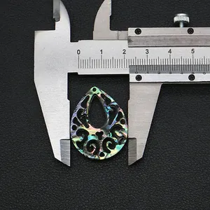 Macro view of teardrop abalone shell pendant measured with caliper showing 24mm width
