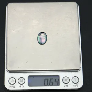 Makro-Detail von ovalem irisierendem Harz-Cabochon mit Muschelglanz wiegt 0.64g auf Digitalwaage
