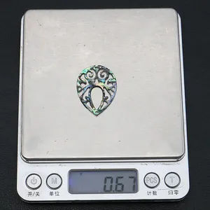 Macro view of abalone shell teardrop pendant showing detailed weight on a scale