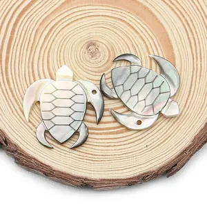 Natural black mother of pearl turtle pendant for jewelry making on wooden background