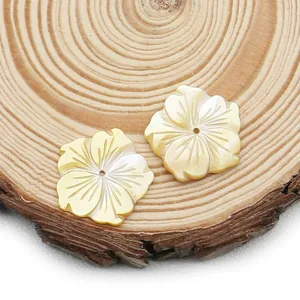 Carved yellow shell flower beads for DIY jewelry making on a wooden background