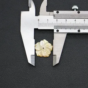 Detail view of 15mm carved flower shell bead being measured with a caliper
