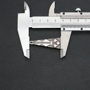 Macro di un ciondolo a trapezio da 37 mm con motivi incisi e misurazione con calibro metallico