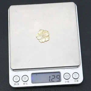 Detailed macro view showing a 1.29g carved shell flower bead on a digital scale for DIY