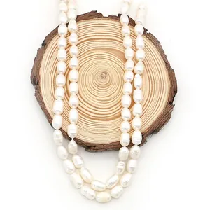 Double-layered necklace with natural cream-white rice-shaped pearls on a rustic wood slice