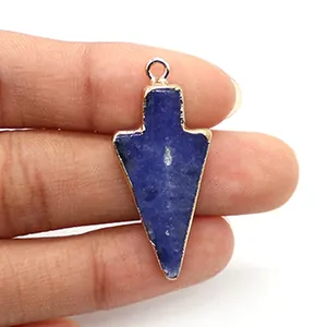 Pijlvormige blauwe natuurstenen hanger met vergulde rand vastgehouden voor de grootte