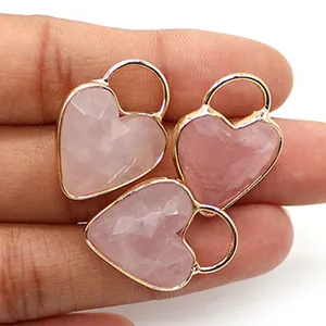 Primo piano di ciondoli a cuore in quarzo rosa sfaccettato con bordo dorato tenuti in mano