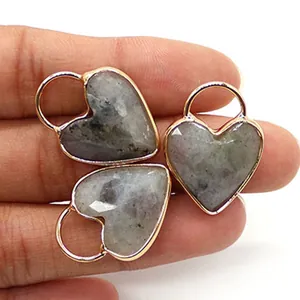 Tre ciondoli a cuore in labradorite sfaccettata con bordo dorato tenuti in mano