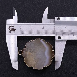 Dettaglio ciondolo in agata rotonda con bordo dorato misurato a 3,1 cm con calibro