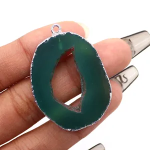 Macro detail of dark green agate slice pendant with silver plated edges held in hand