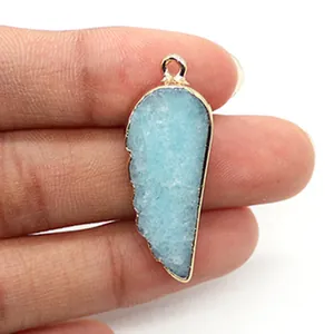Détail d'un pendentif en pierre bleue en forme de plume avec bordure dorée métallique