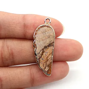 Pendentif en pierre naturelle en forme d'aile avec bordure dorée tenu à la main