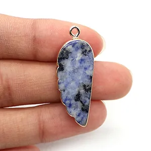 Vue macro détaillée du pendentif en pierre bleue en forme de plume aux bords dorés