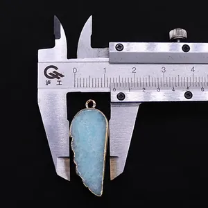 Macro montrant la mesure de largeur d'un pendentif plume en pierre bleue avec bord doré