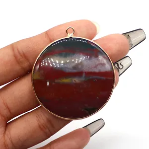 Macro shot of circular natural stone pendant with gold edge held by a hand