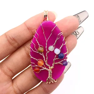 Handvastgehouden levensboom hanger van fuchsia natuursteen met gouden draadwikkel