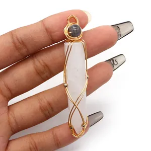 Close-up of handmade gold wire-wrapped hexagonal white crystal pendant held by hand