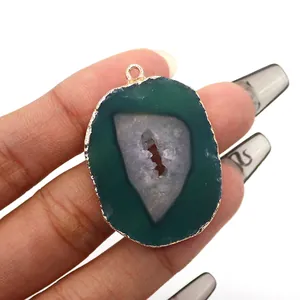 Detail of natural green agate slice pendant with gold plated edge held in hand