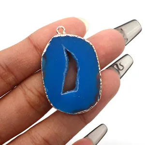 Detail of blue natural agate slice pendant with gold plated edge held in hand