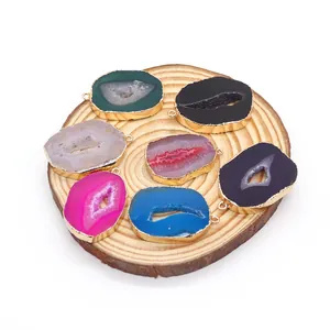Set of 7 colorful natural agate slice pendants with gold plated edges on wood