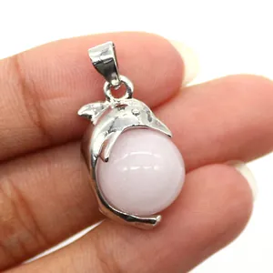 Close-up of a silver dolphin pendant holding a round pink natural stone on a person's hand