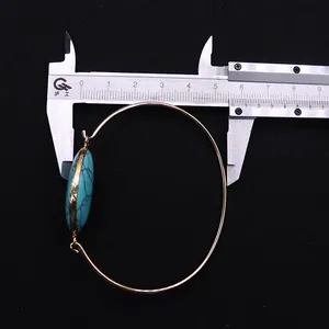 Macro detail of gold plated open bangle with natural turquoise stone and measuring tool