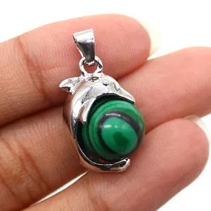 Detailed macro view of a silver dolphin pendant wrapping a green malachite stone bead