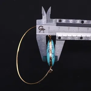 Macro view of gold plated turquoise stone earring thickness measured with a caliper