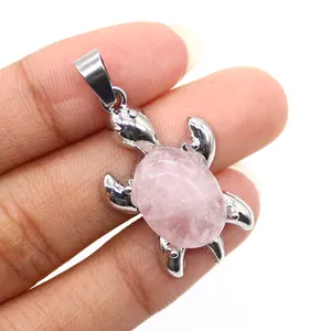 Dettaglio ravvicinato di un ciondolo a tartaruga in pietra rosa con cornice in argento