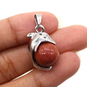 Macro view of a silver dolphin pendant featuring a reddish-brown goldstone bead inlay