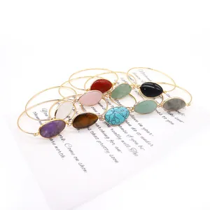 Gold plated open bangles with oval natural stones in multiple colors on a white art card