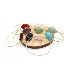 Stack of gold-plated bracelets featuring colorful oval natural stones in various shades