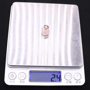 Macro view of a 2.4g cube-cut pink rose quartz pendant on a digital scale for measurement