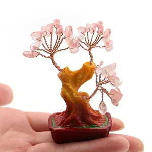 Macro-opname van een kleine roze kristallen geluksboom in een rode pot op hand