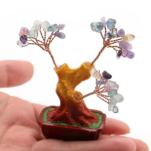 Handgemaakte mini kristallen geluksboom in de hand gehouden voor schaal en steendetails