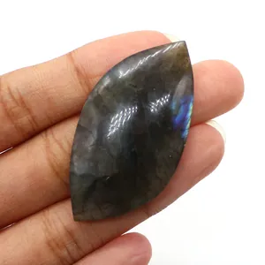 Macro view of marquise-cut labradorite stone with blue flash held in hand for scale