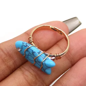 Detail van een handgemaakte gouden ring met een blauwe visvormige turquoise steen