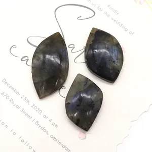 Three marquise-shaped labradorite stones with blue fire on a white invitation card